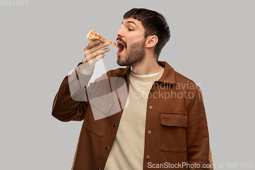 Image of hungry young man eating pizza