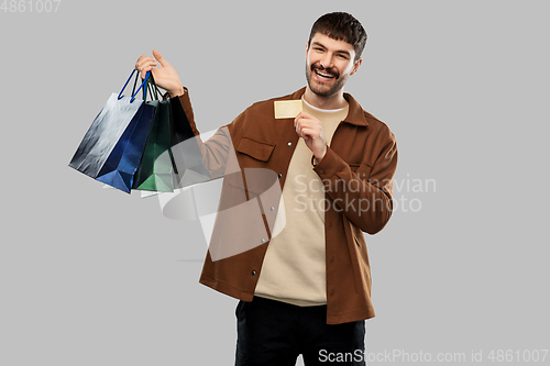 Image of happy young man with shopping bags and credit card