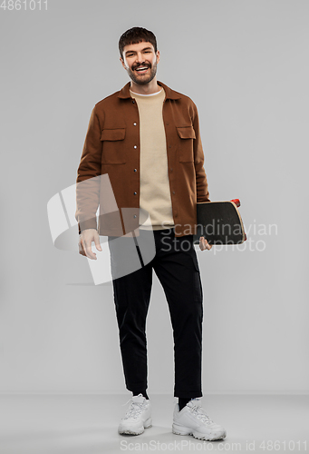 Image of smiling young man in brown jacket with skateboard