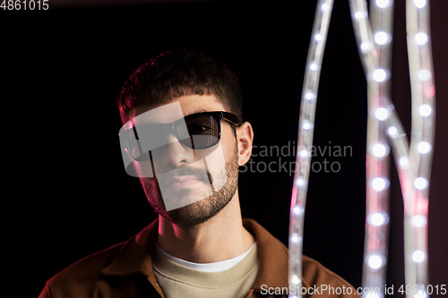 Image of man in sunglasses over neon lights at nightclub