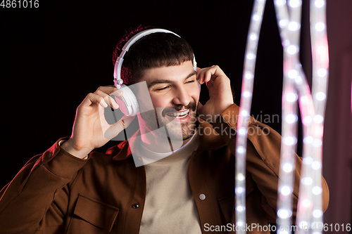 Image of man in headphones over neon lights of night club