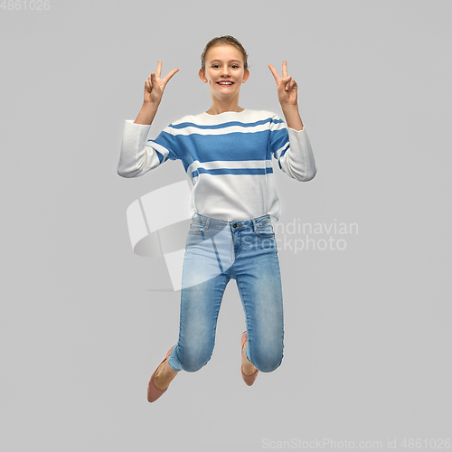Image of smiling teenage girl jumping and showing peace