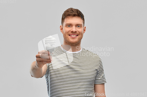 Image of smiling young man holding lighting bulb