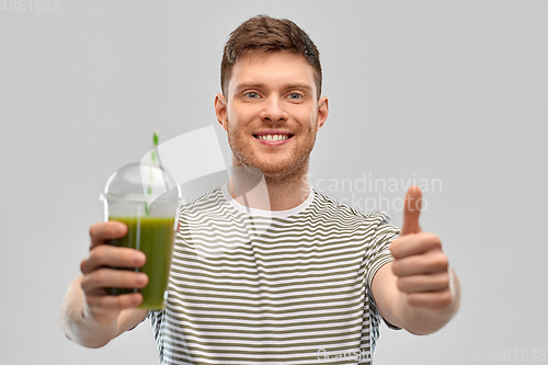 Image of happy man with green smoothie showing thumbs up