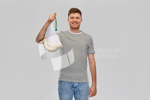 Image of happy man holding reusable string bag with bananas