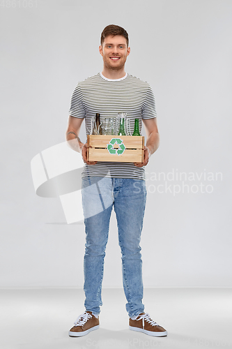 Image of smiling young man sorting glass waste