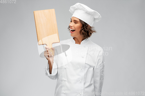 Image of smiling female chef in toque with cutting board