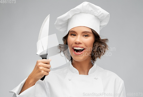 Image of smiling female chef in toque with kitchen knife
