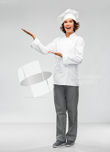 Image of smiling female chef holding something on hand