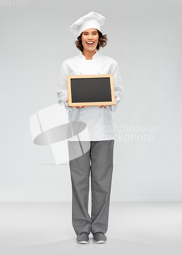 Image of smiling female chef holding black chalkboard