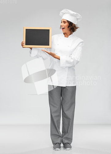 Image of smiling female chef holding black chalkboard