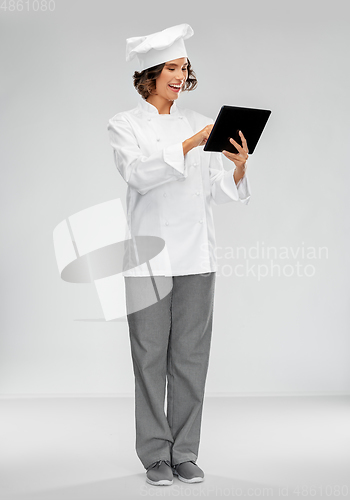 Image of smiling female chef in toque with tablet computer