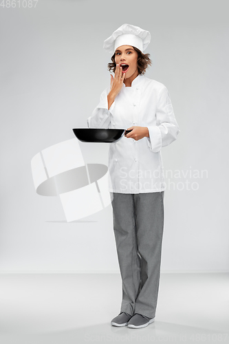 Image of surprised female chef in toque with frying pan