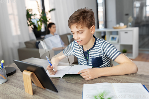 Image of student boy with tablet computer learning at home