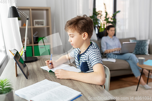 Image of student boy with tablet computer learning at home