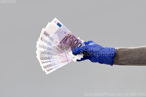 Image of close up of hand in medical glove with money