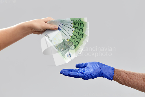 Image of close up of hand in medical glove giving money