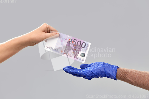 Image of close up of hand in medical glove giving money