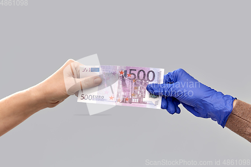 Image of close up of hand in medical glove giving money