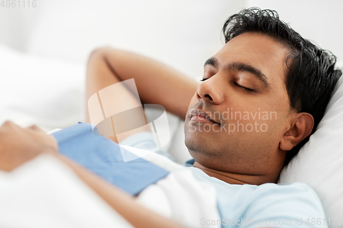 Image of indian man with book sleeping in bed at home