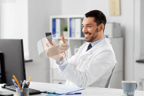 Image of doctor with smartphone having video call at clinic