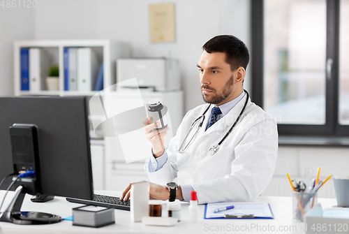 Image of male doctor with medicine and computer at hospital