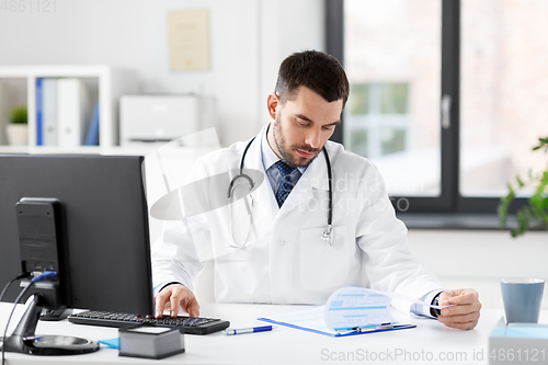 Image of doctor with clipboard and computer at hospital