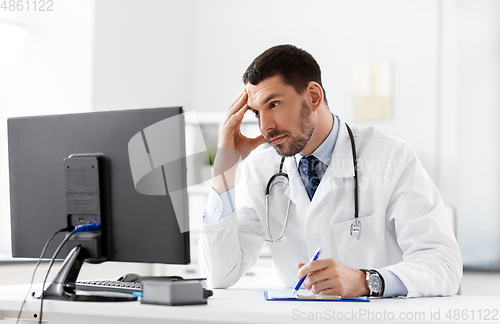 Image of doctor with clipboard and computer at hospital