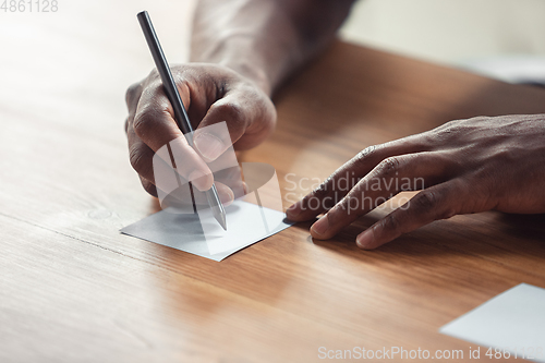 Image of Close up of african-american male hands, working in office