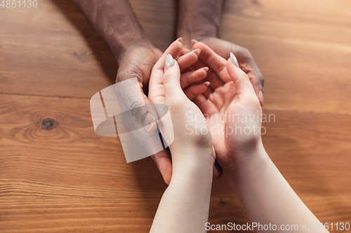 Image of Close up of african-american male and caucasian female hands holding
