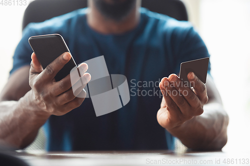 Image of Close up of african-american male hands, working in office