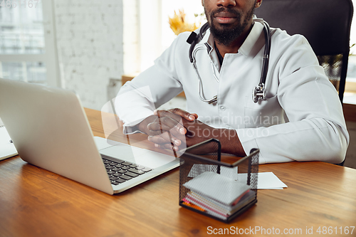 Image of African-american doctor consulting for patient, working in cabinet