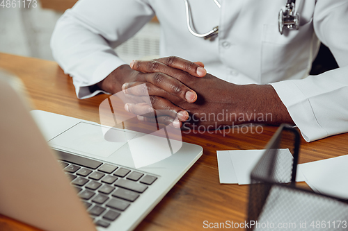 Image of African-american doctor consulting for patient, working in cabinet, close up