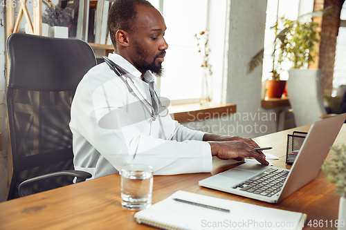 Image of African-american doctor consulting for patient, working in cabinet