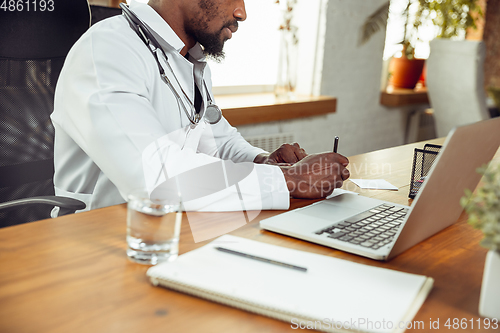 Image of African-american doctor consulting for patient, working in cabinet, close up