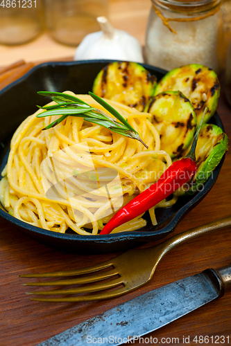 Image of italian spaghetti pasta with zucchini sauce on iron skillet