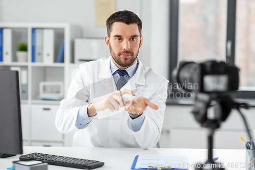 Image of doctor with hand sanitizer recording video blog