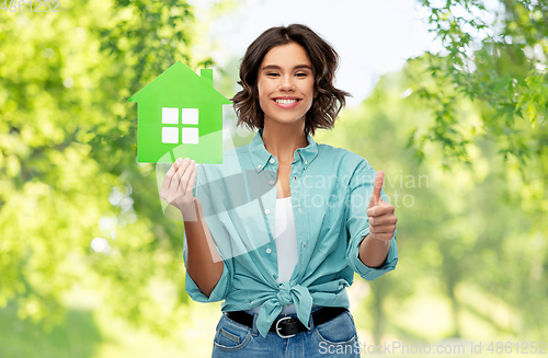 Image of smiling woman with green house showing thumbs up