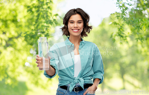 Image of smiling young woman holding water in glass bottle