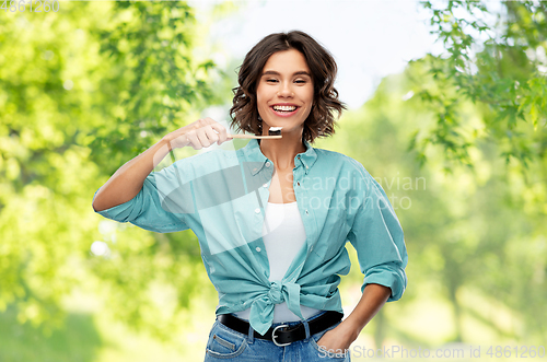 Image of smiling woman with toothpaste on wooden toothbrush