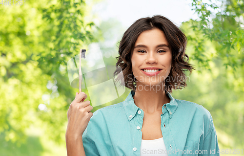 Image of smiling young woman with wooden toothbrush