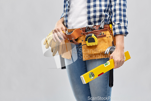 Image of woman builder with level and working tools on belt