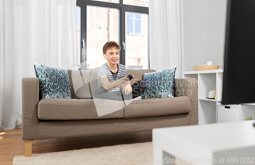 Image of happy boy with remote control watching tv at home