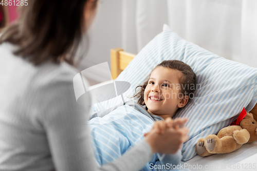 Image of mother and happy little daughter in bed at home