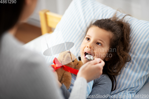 Image of mother giving cough syrup to sick daughter