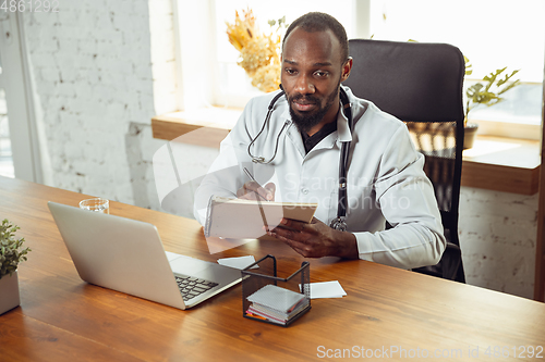 Image of African-american doctor consulting for patient, working in cabinet, close up