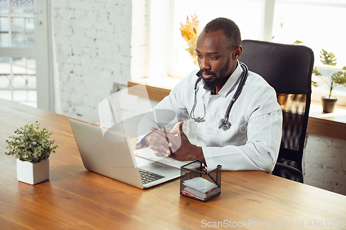 Image of African-american doctor consulting for patient, working in cabinet, close up