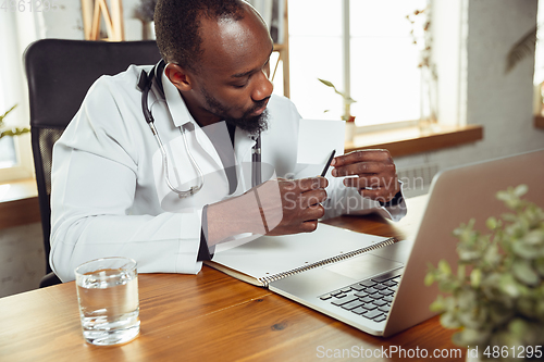 Image of African-american doctor consulting for patient, working in cabinet, close up