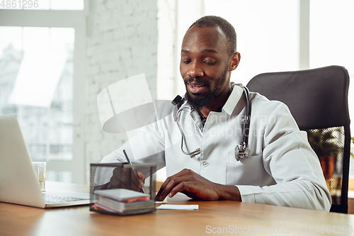 Image of African-american doctor consulting for patient, working in cabinet, close up