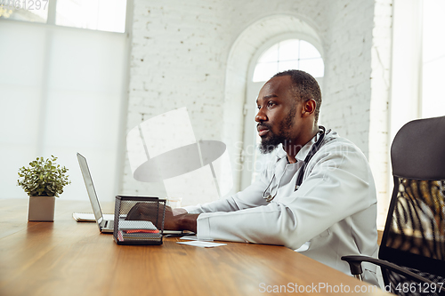 Image of African-american doctor consulting for patient, working in cabinet, close up